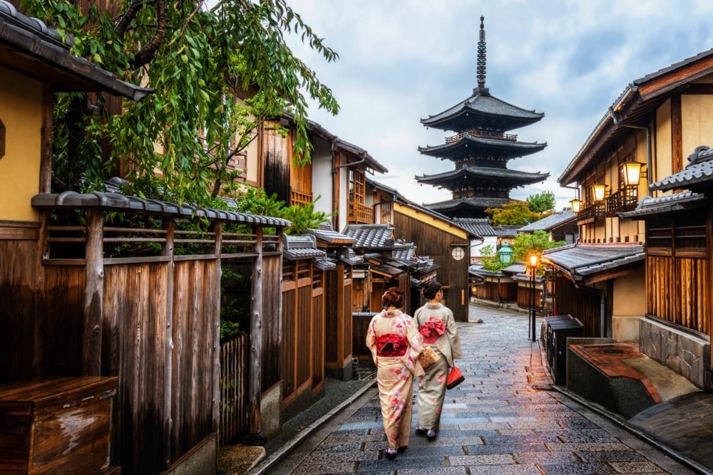 Two women in traditional kimonos walk through a Kyoto street