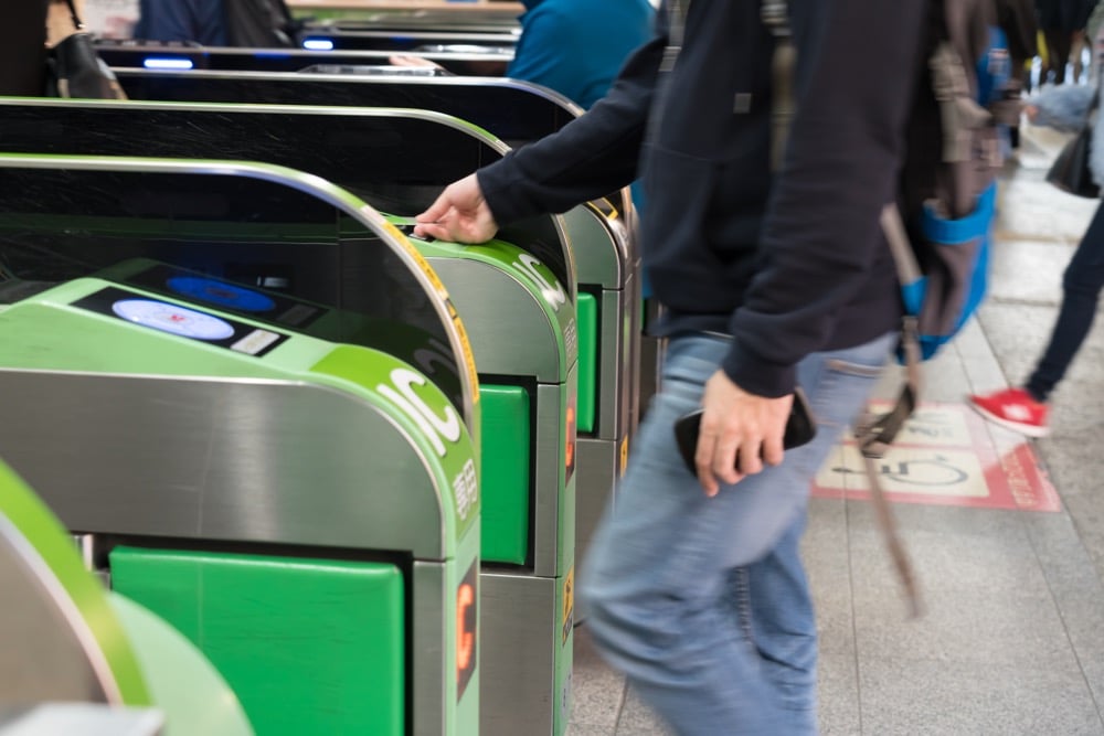 Hand inserting a Suica transit card into a ticket machine