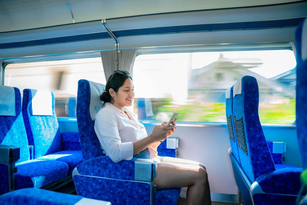 A woman using her smartphone on a Shinkansen, enjoying Wi-Fi during her trip
