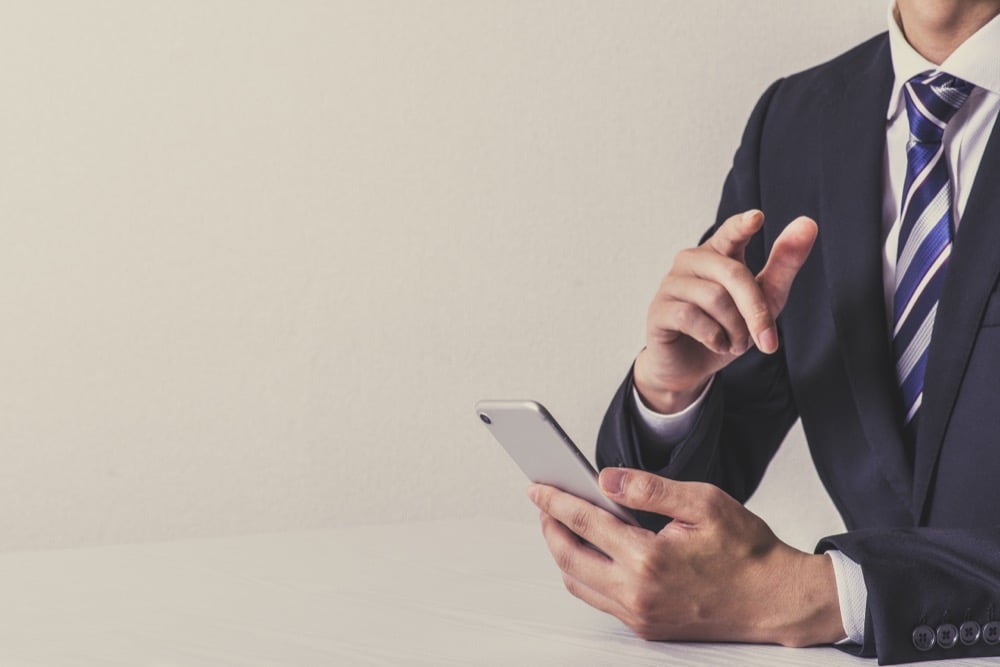A businessman in a suit checking smartphone compatibility before purchasing a Japan SIM card