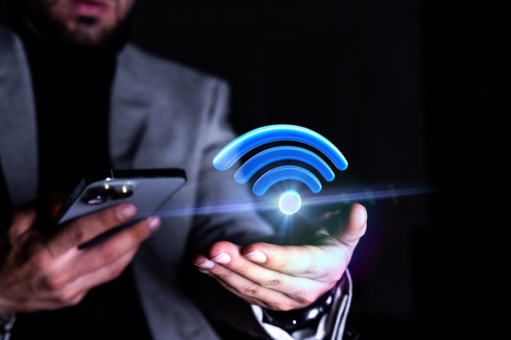 Man holding a phone with a glowing Wi-Fi hologram