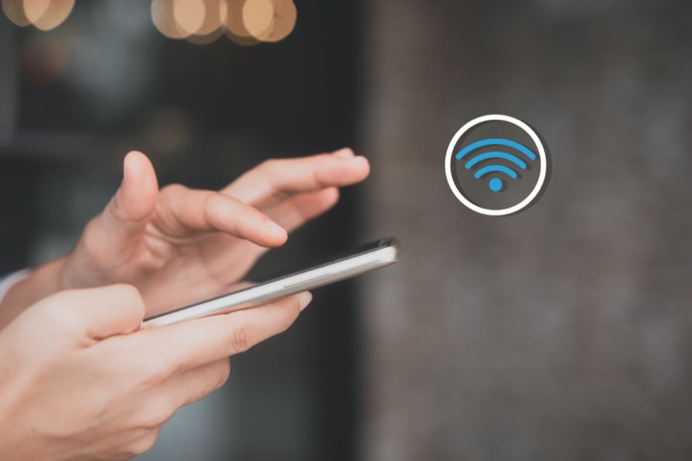 Hands using a smartphone with a floating Wi-Fi icon