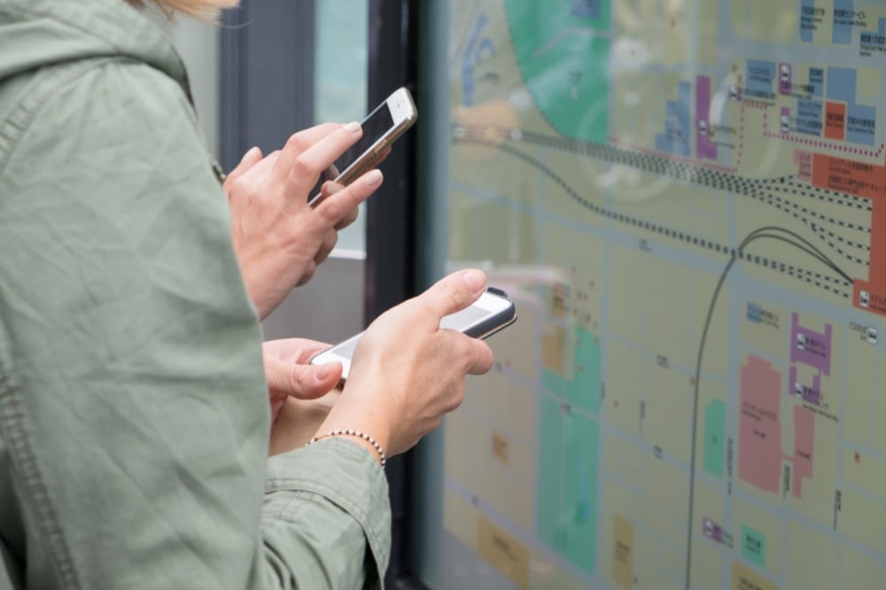 Two people using smartphones to navigate with a city map
