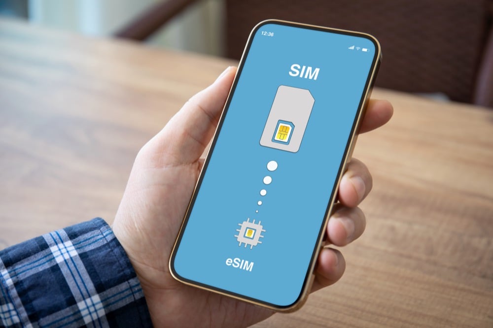 A hand holding smartphone showing conversion from SIM to eSIM graphic