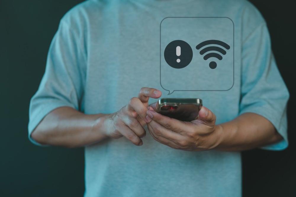 Hands holding smartphone with a floating Wi-Fi error notification icon