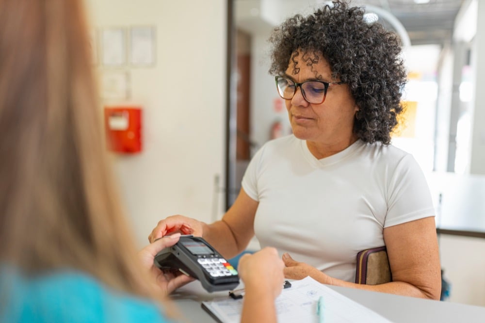 A hand holding a green and white Suica transit IC card