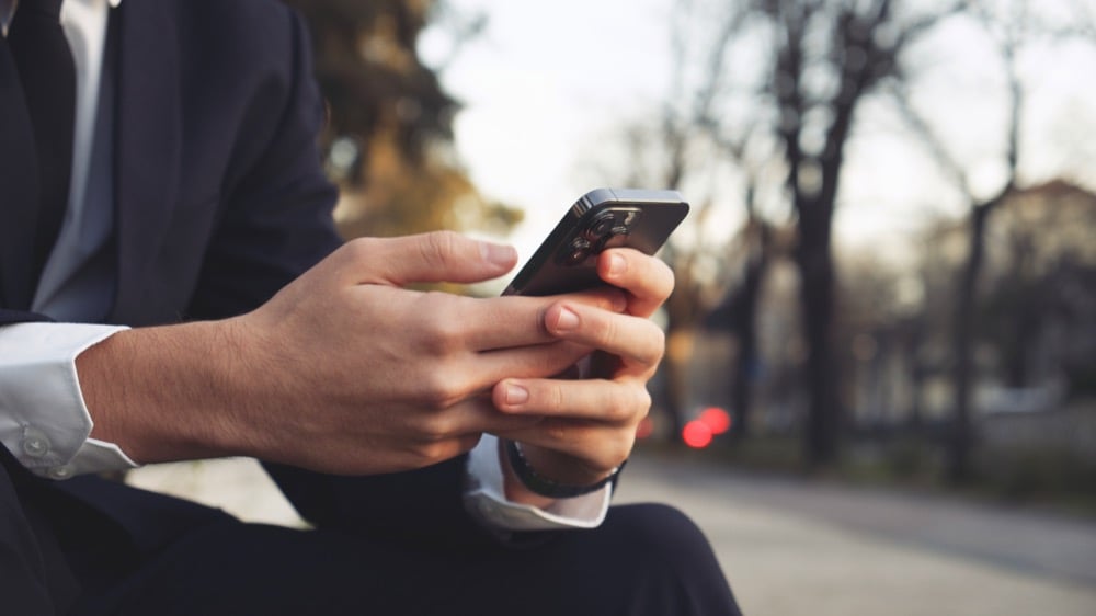 A person in a suit using a smartphone outdoors
