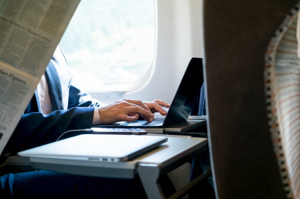 A passenger typing on a laptop while riding the Shinkansen