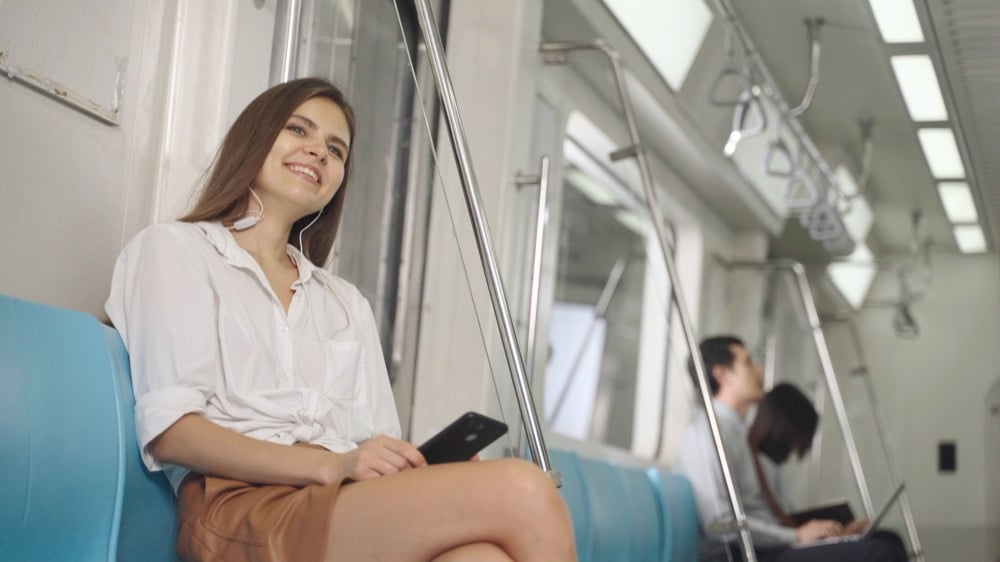Woman on a train smiling at her phone