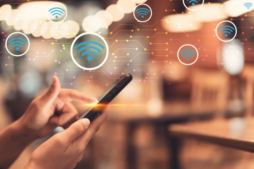 Hands using a smartphone with connected Wi-Fi icons in the background
