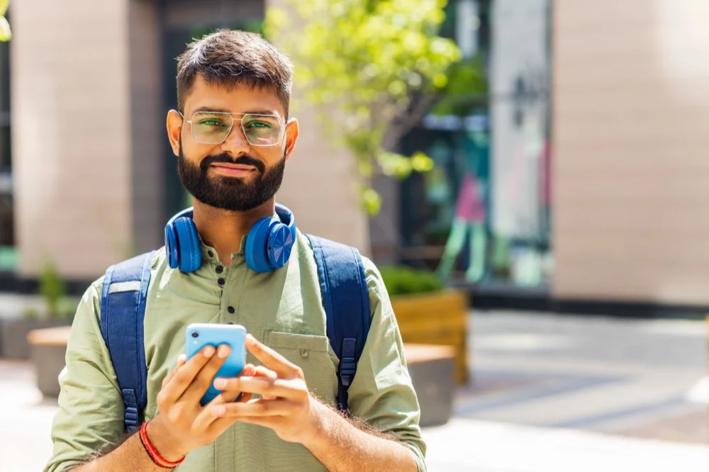 Man smiling with a phone in an outdoor plaza