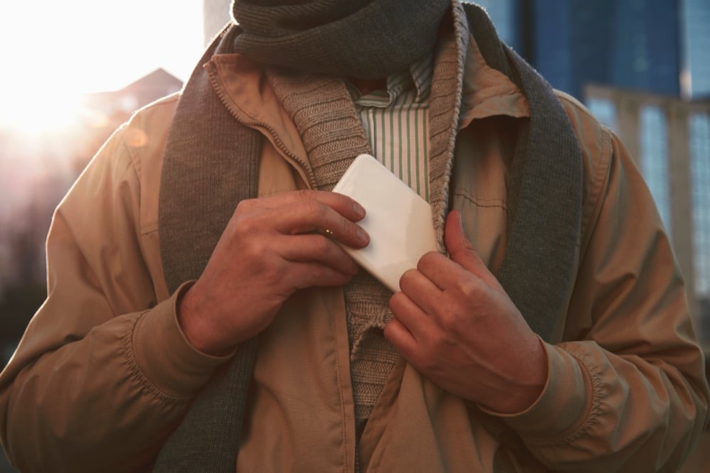A traveler tucking a pocket Wi-Fi device into their jacket while exploring a city