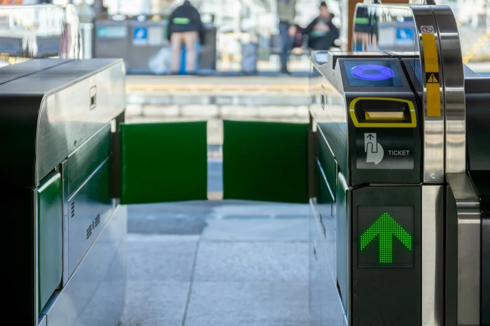 An open ticket gate at a Japanese train station showing a green arrow for Suica card entry