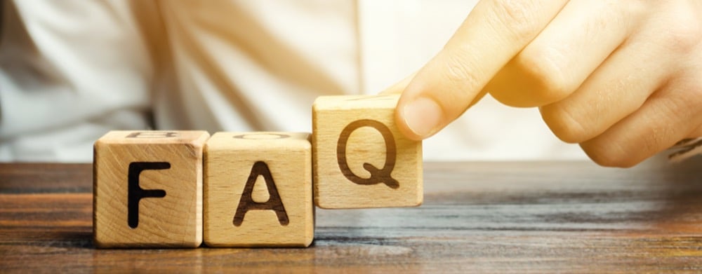 A hand arranging wooden blocks to spell out the word FAQ