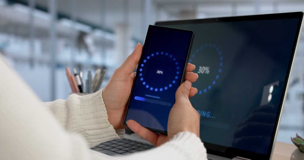 A person holding smartphone with a thirty percent download progress screen