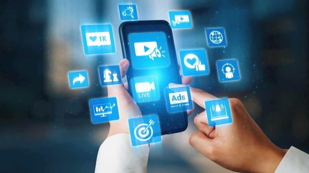 A person using smartphone with floating digital media and marketing icons