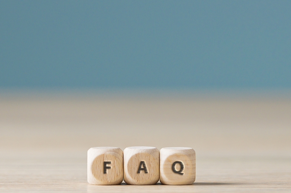 Three wooden blocks spelling FAQ against a blue background