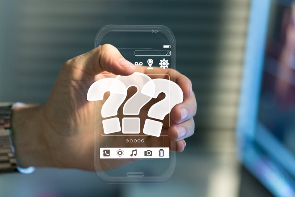 Hand holding transparent digital phone showing three large question marks