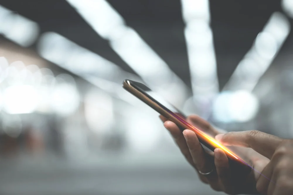 Hands holding a glowing smartphone against a blurred background