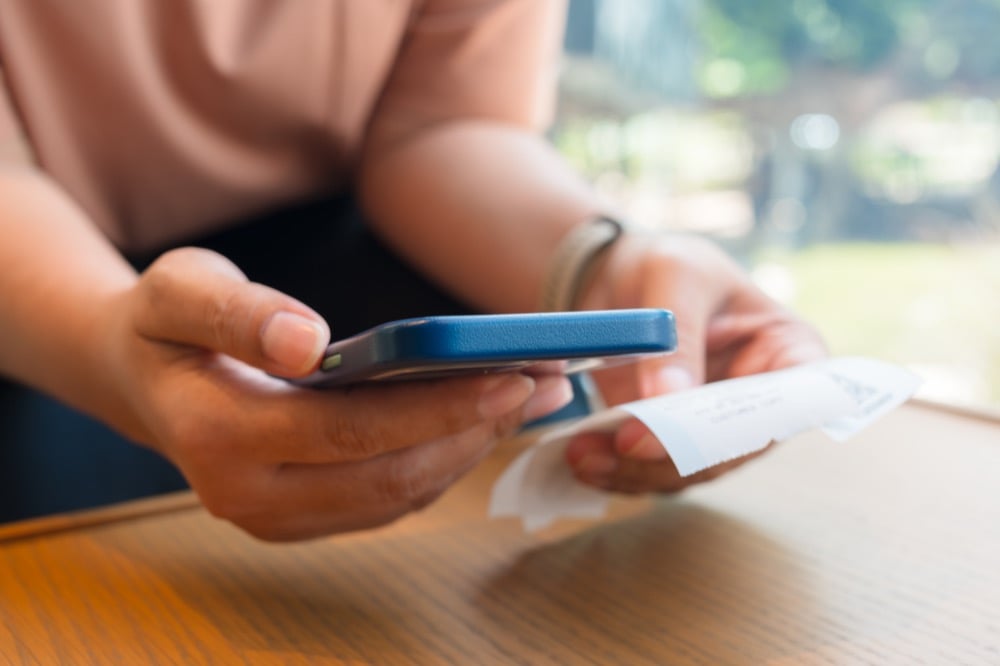 Hands holding a smartphone and a receipt while reviewing ANA in-flight Wi-Fi pricing