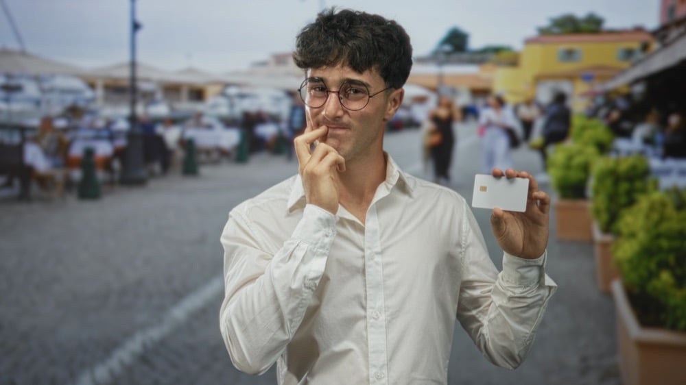 A thoughtful man holding a card while considering how to set up Mobile Suica for Japan travel