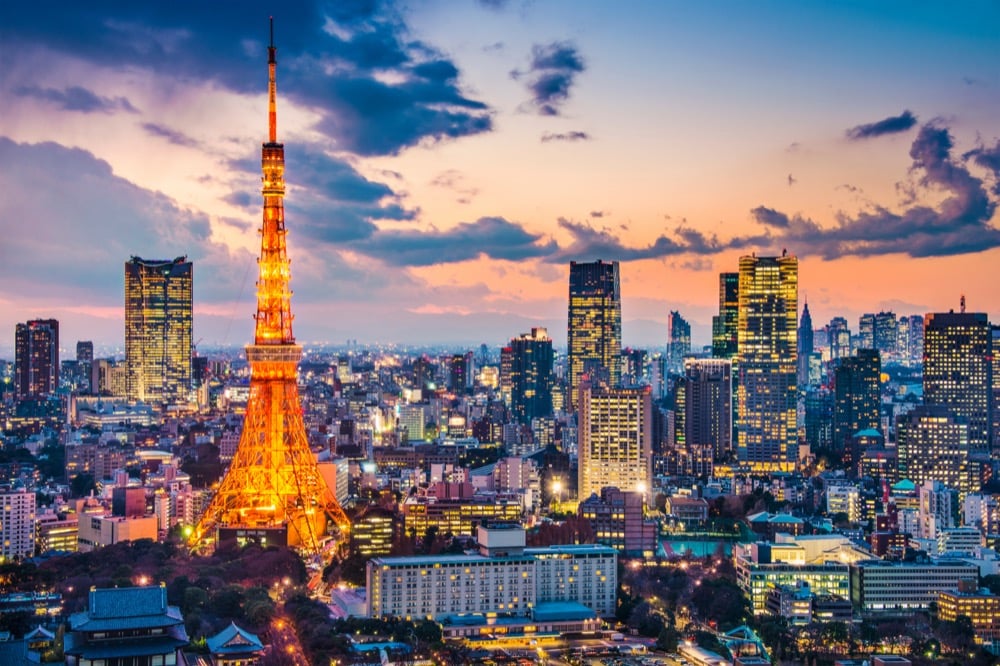 Tokyo Tower illuminated at dusk with the city skyline and colorful sunset sky in the background