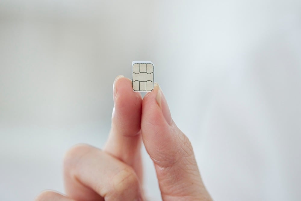 A close-up of fingers holding a nano SIM card for Japan travel