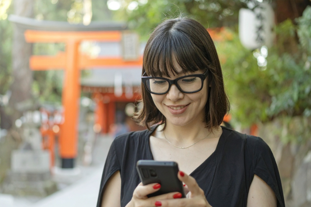 A tourist checking their phone at a shrine in Japan