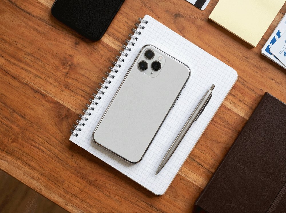 iphone 13 pro lying on notebook with pen closeup