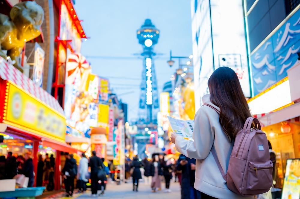 A woman is looking at a physical map on a city street in Osaka