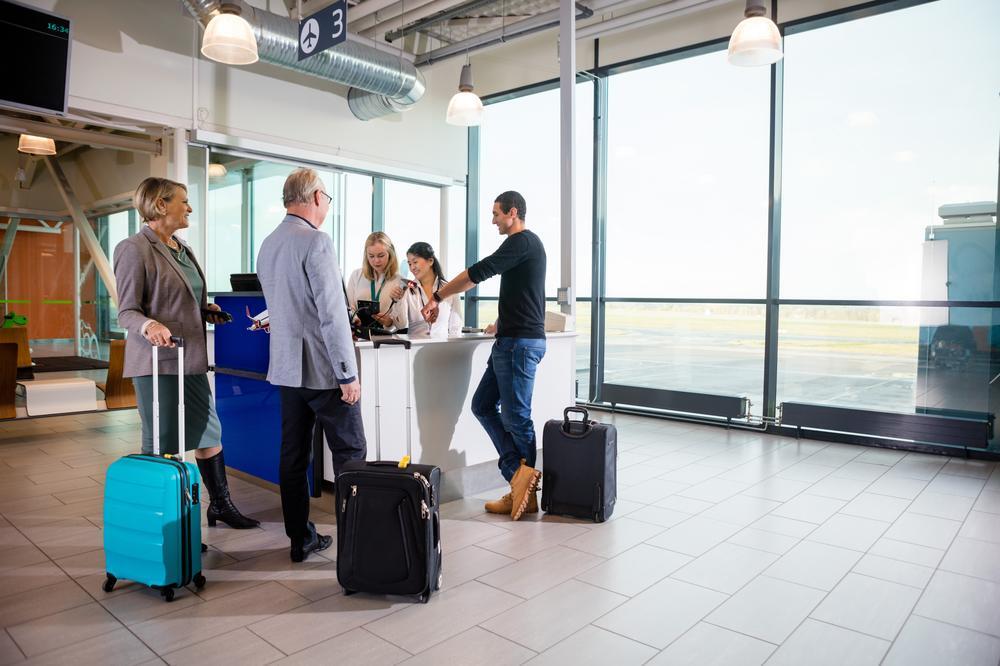 A group of travelers with are interacting with airport staff at a counter