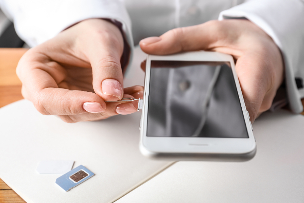 A person inserting a SIM card into a smartphone