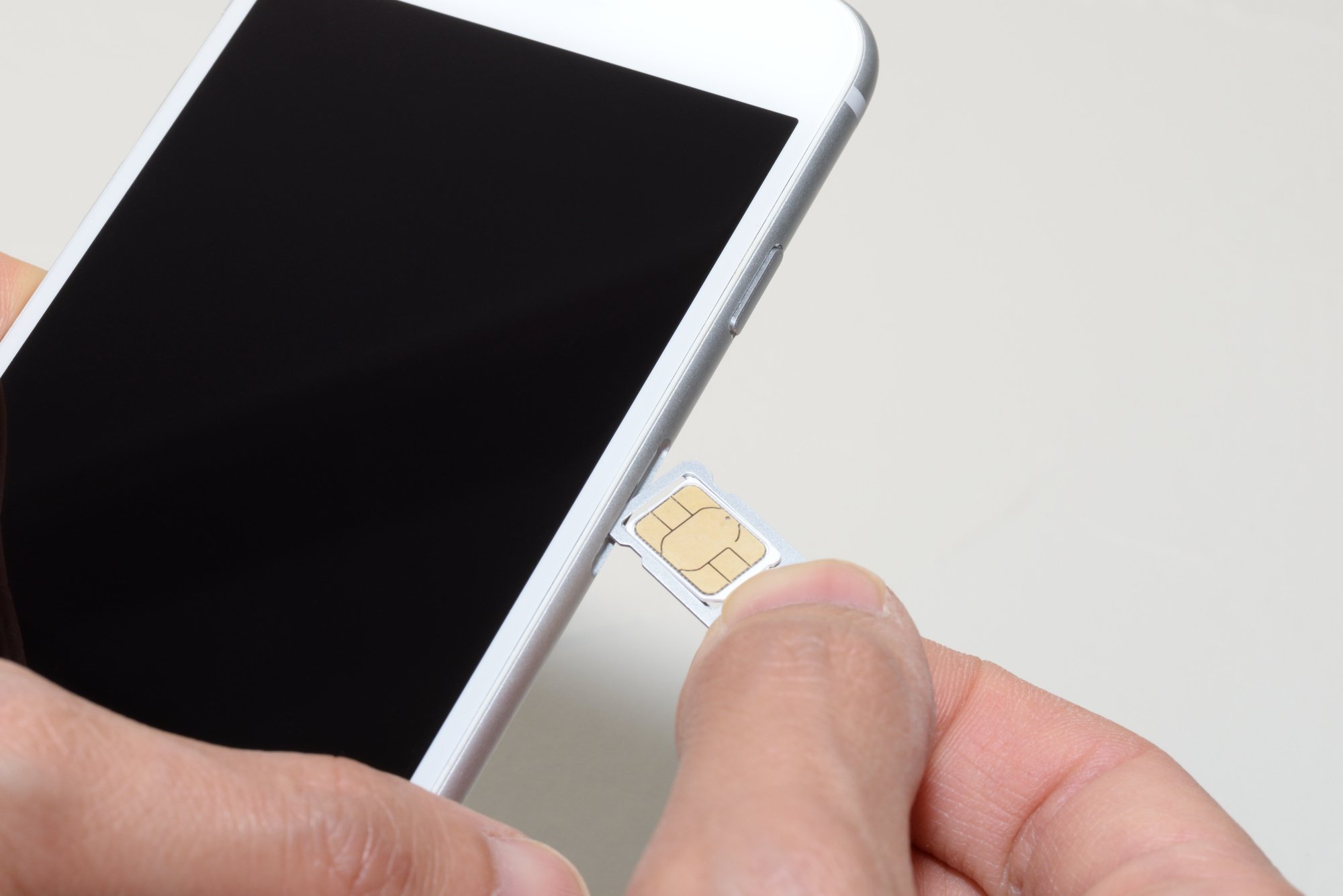 A person inserting a SIM card into a smartphone