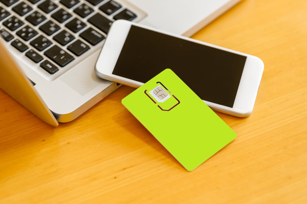 An eSIM is gently placed on the surface of a smartphone